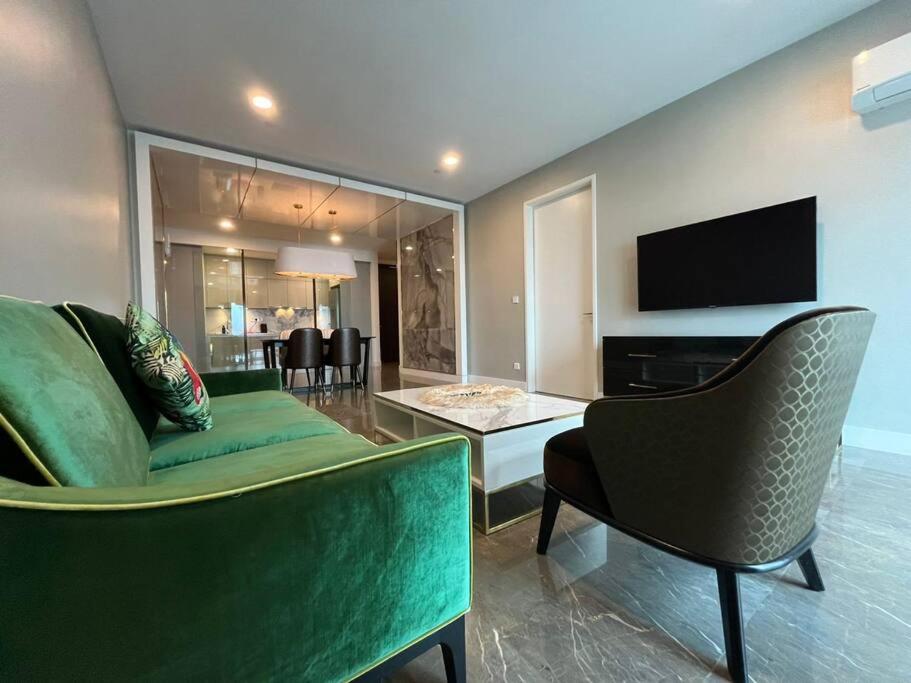 a living room with a green couch and a television at Facestyle Infinity Pool KLCC Smart TV Free WiFi Two Bedroom in Kuala Lumpur