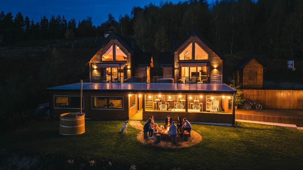 un gruppo di persone che si trovano di fronte a una casa di notte di Cortina resort a Ivanjica