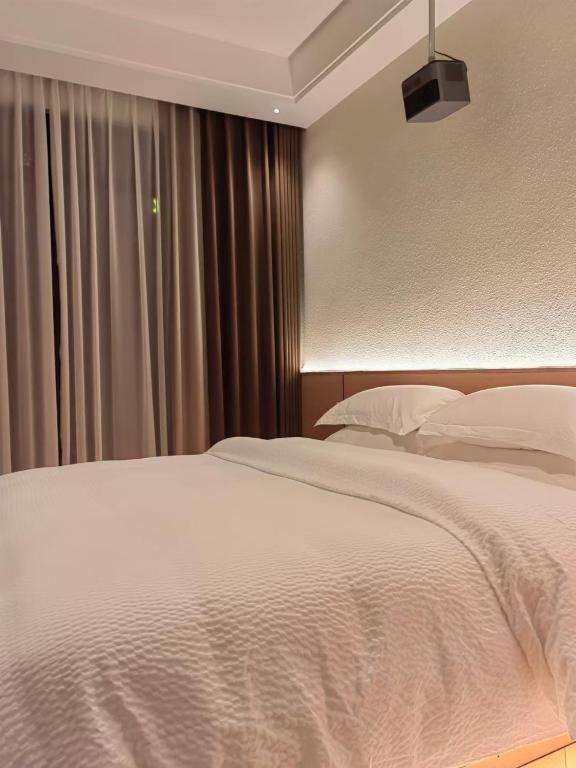 a bedroom with a white bed and a window at Flower Whisperer Homestay Tianmenshan Store free airport and station pick-up in Zhangjiajie