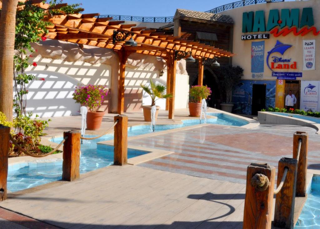 a patio with a wooden pergola and a swimming pool at Naama Inn Hotel in Sharm El Sheikh