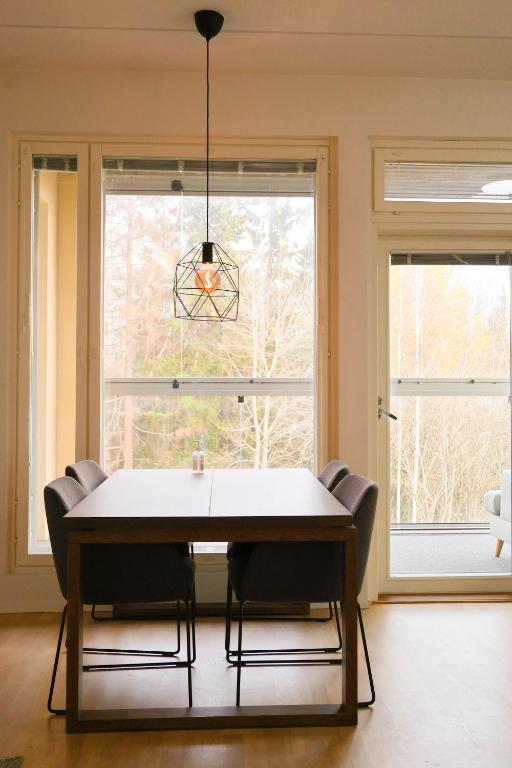 a dining room with a table and chairs in front of a window at Modern 2-Bedroom Apartment with Sauna, Forest View & Parking in Espoo
