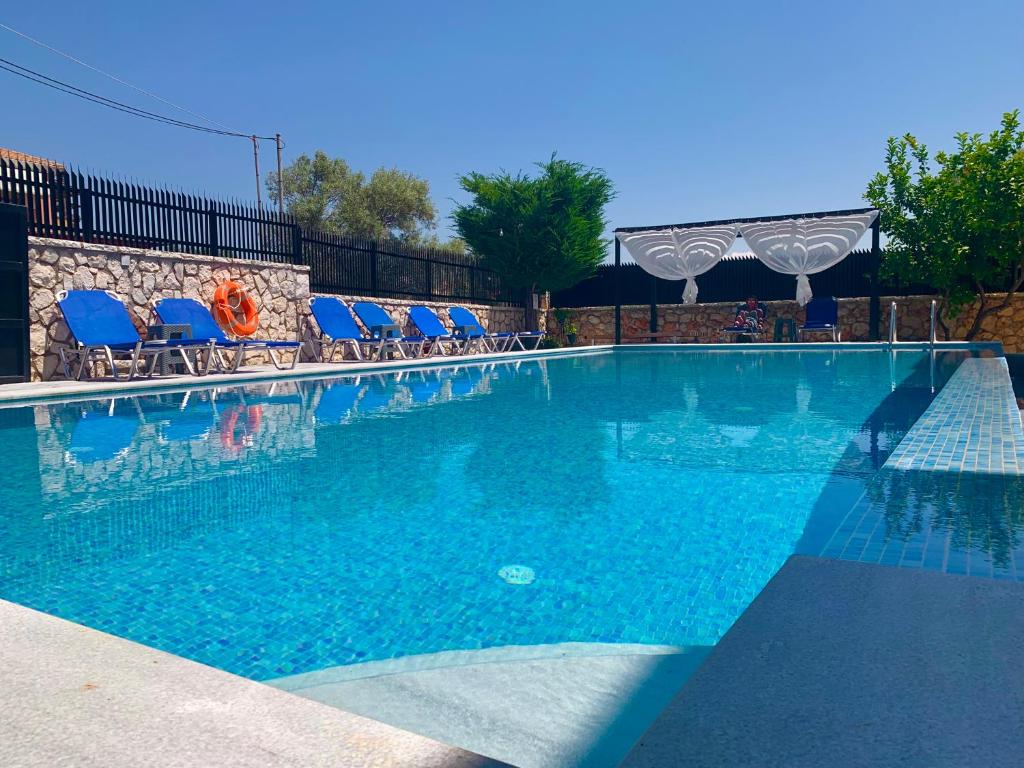 a large swimming pool with blue lounge chairs in it at Alkionis Garden View Apartments in Lefkada