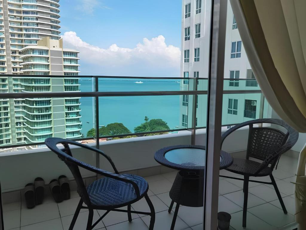 two chairs and a table on a balcony with a view of the ocean at Mansion One Luxurious Seaview Vacation Homes in George Town