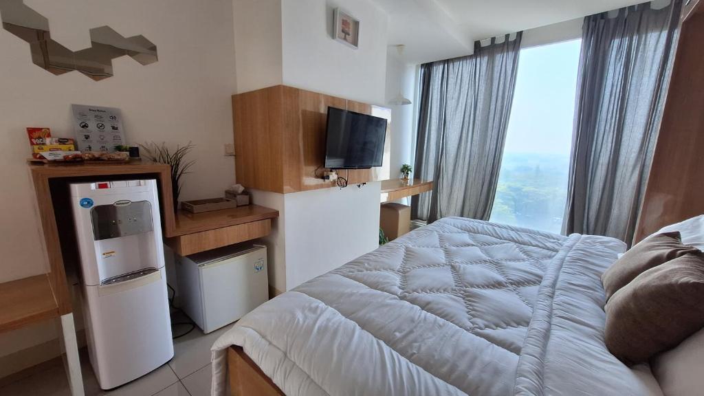 a bedroom with a bed and a tv and a window at 7 min to ICE 1BR with Wifi, Netflix, AC, Kitchen, TV, Swimming Pool, Gym, Free Parking in Dadap