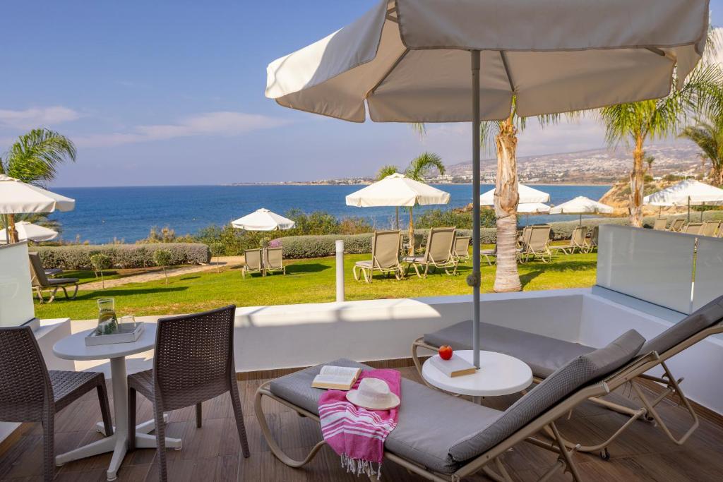 a patio with a table and chairs and an umbrella at Queens Bay Hotel in Paphos