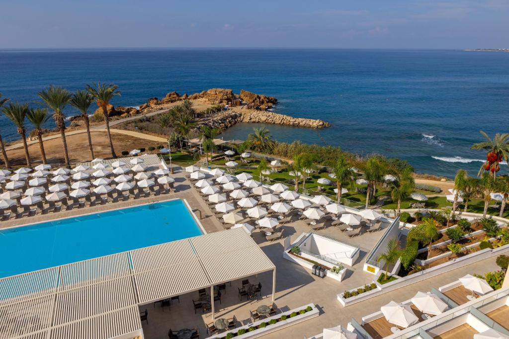 an aerial view of a resort with a swimming pool and the ocean at Queens Bay Hotel in Paphos