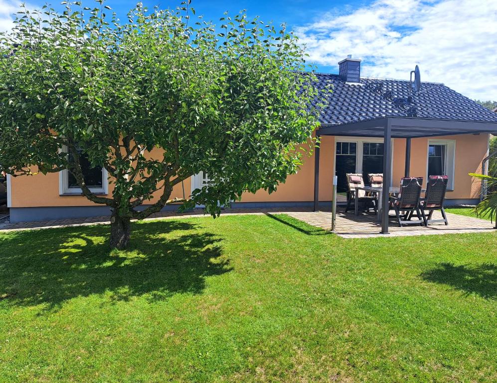 a house with a tree and a table and chairs at Ferienhaus Michelson in Ostseebad Karlshagen