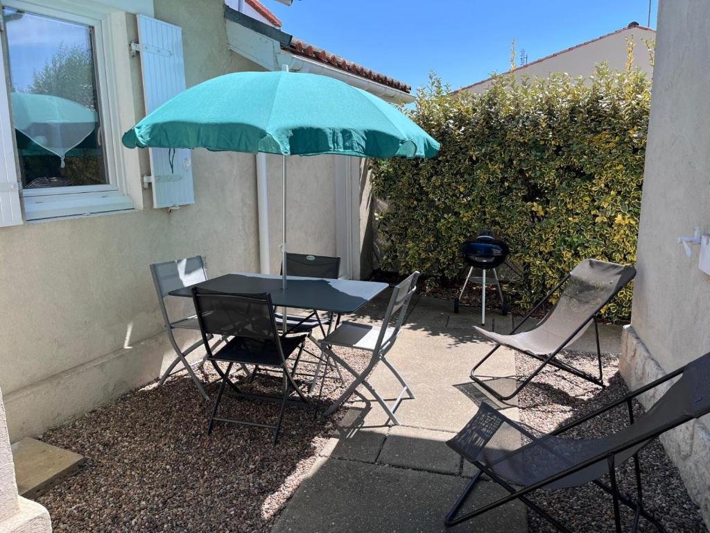 une table et des chaises avec un parasol vert et un grill dans l'établissement MAISON SAINT PALAIS SUR MER, à Saint-Palais-sur-Mer