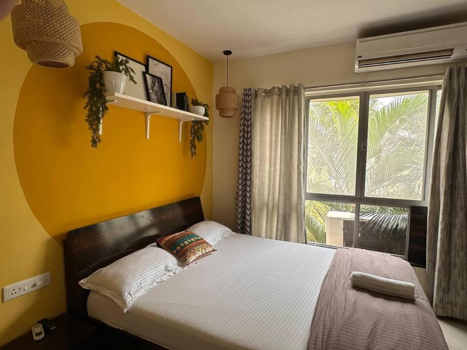 プネにあるSunflower Pvt Studio Room in Koregaon Park with AC WiFi Smart TVのベッドルーム1室(黄色い壁のベッド1台、窓付)