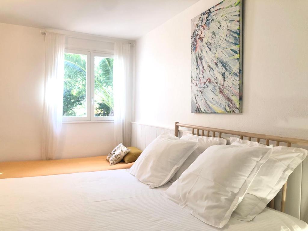 a bedroom with a bed with white pillows and a window at L’appartement - Jardin Secret in Marseille