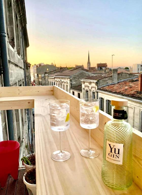 - une bouteille de vin et deux verres sur un balcon dans l'établissement Marché des Capucins - Calme - Lumineux - Garage, à Bordeaux