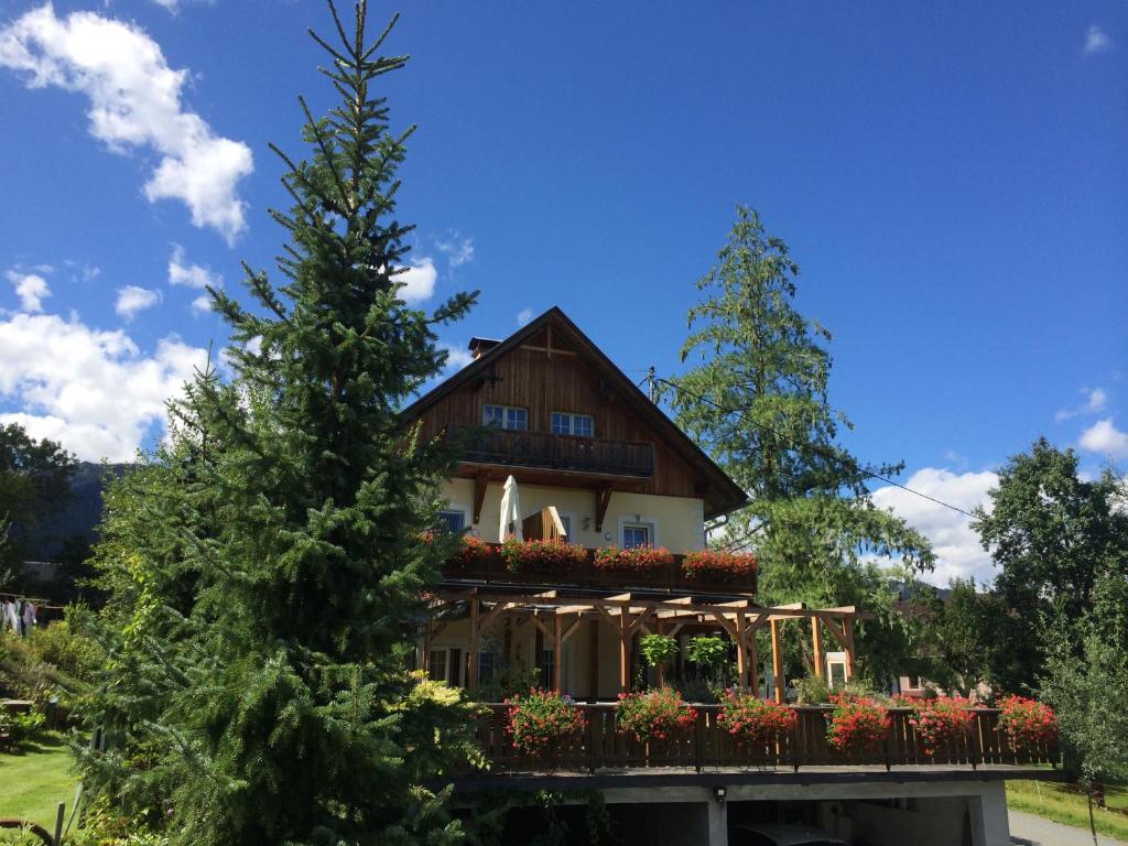 ein Haus mit einem Balkon und einem Baum in der Unterkunft Landhof Schober appartementen & kamers in Weissbriach