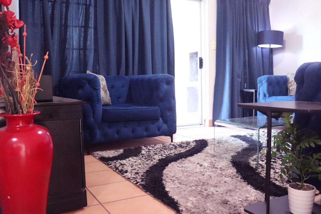 Una sala de estar con un sofá azul y un jarrón rojo. en Affordable Decent Private Room In a Shared Apartment with a Pool, en Sandton