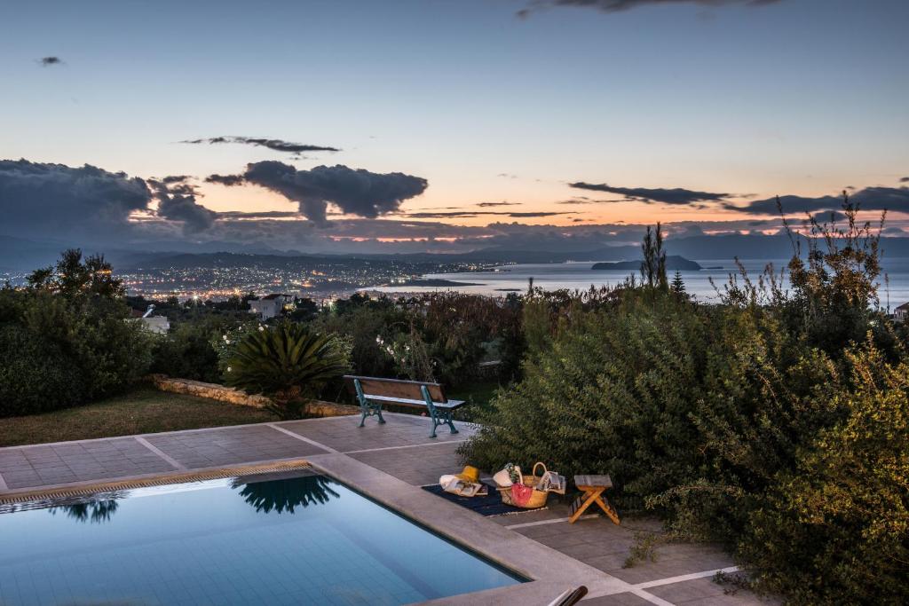 einen Pool mit einer Bank und Stadtblick in der Unterkunft Villa Mariposa - panoramic sea view - near Chania city in Chania