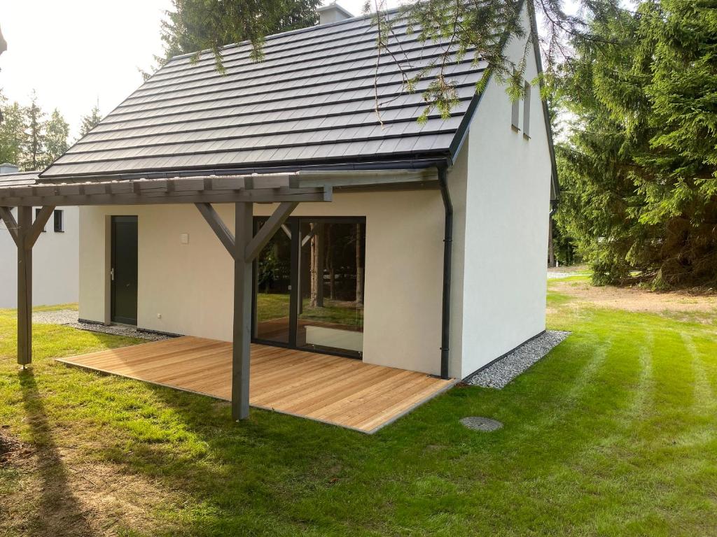 a small white house with a wooden deck at Náš sen - Domek in Svratouch