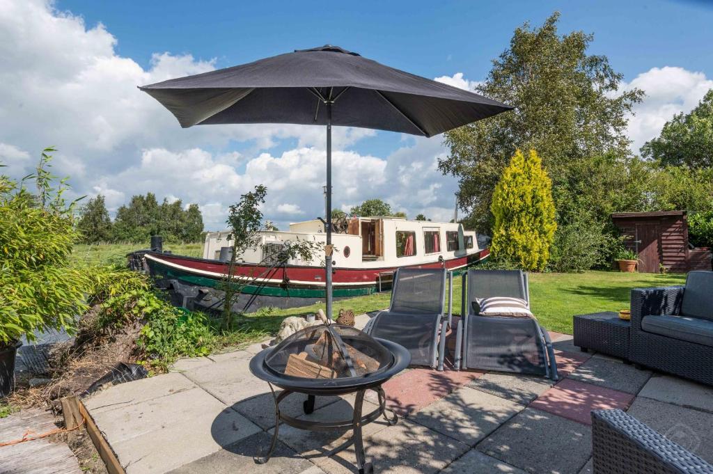 a table with an umbrella on a patio with a boat at Houseboat Vinkeveen in Vinkeveen