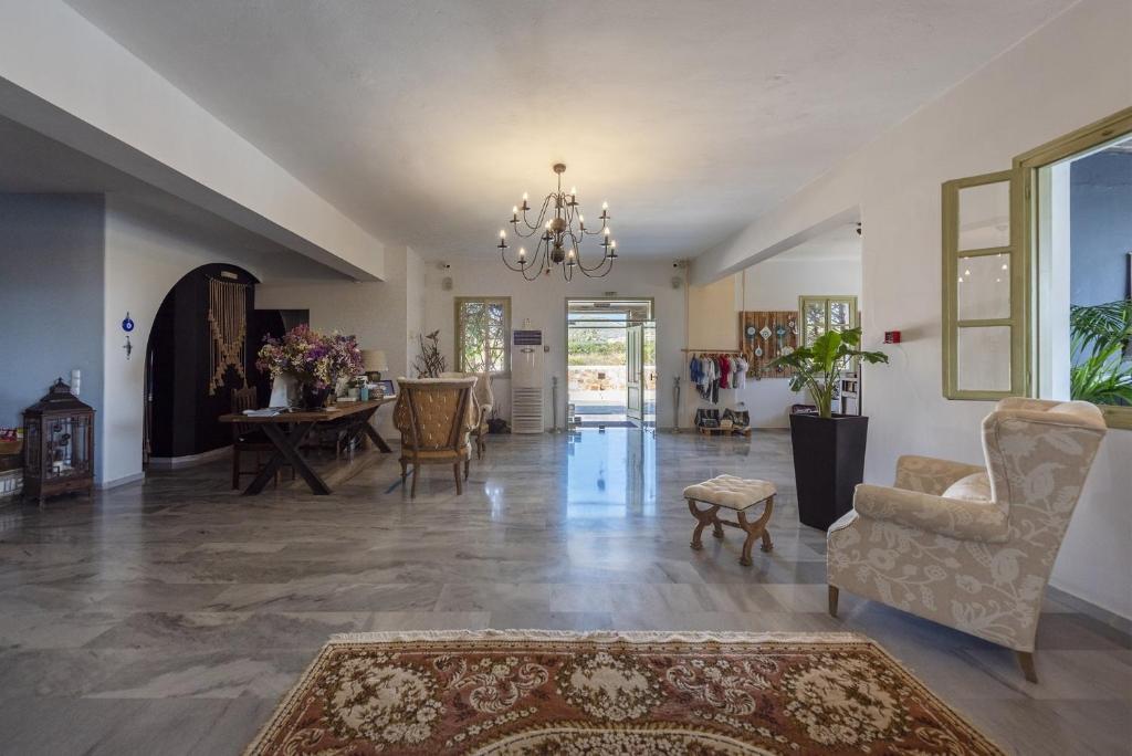 a living room with a chandelier and a table and chairs at Parosland Hotel in Aliki