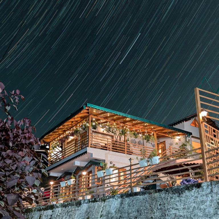 a house in the snow at night with stars at Woody Trails - Astronomy, Graphology, Family, Kainchi Dham in Bhowāli