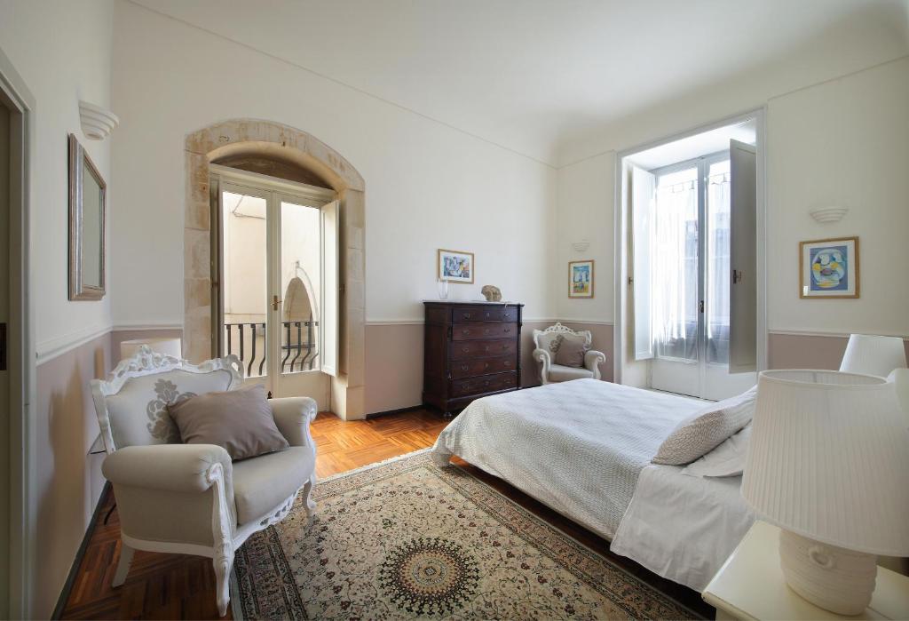 een slaapkamer met een bed, een stoel en een spiegel bij B&B Five Rooms in Siracusa