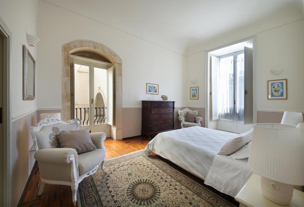 1 dormitorio con cama, silla y espejo en B&B Five Rooms en Siracusa