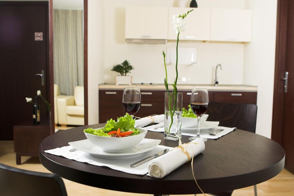 una mesa negra con un tazón de ensaladas y copas de vino en Apartamentai Tylios pušys, en Palanga