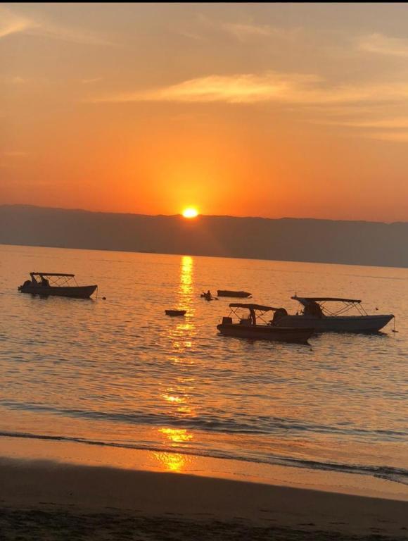 two boats on the water at sunset on the beach at Suítes Encanto do Pai in Praia de Araçatiba