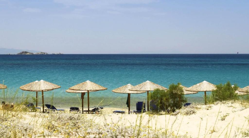 a group of umbrellas on a beach with the ocean at Ploes Seaside Houses in Plaka
