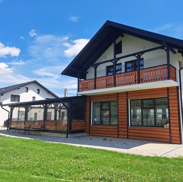 Una casa grande con un balcón en la parte superior. en Căsuța din livadă, en Capu Cîmpului