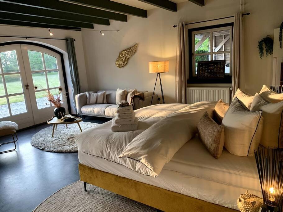 a bedroom with a large bed and a couch at Mastbos Estate Carriage House in Breda
