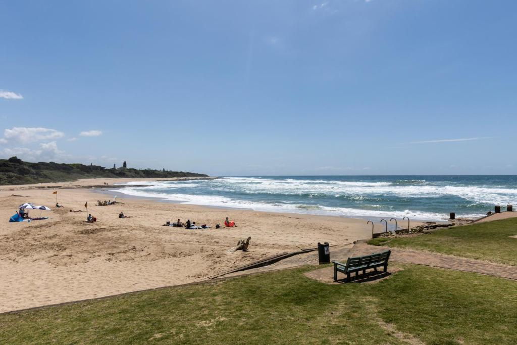 a group of people on a beach near the ocean at Michael Point 6 in Shelly Beach