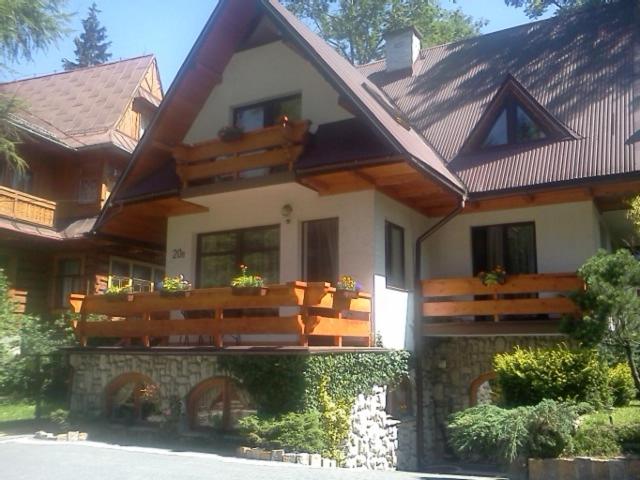 ein großes Haus mit einem Holzdach und einer Veranda in der Unterkunft Pokoje Gościnne U Wandy in Zakopane