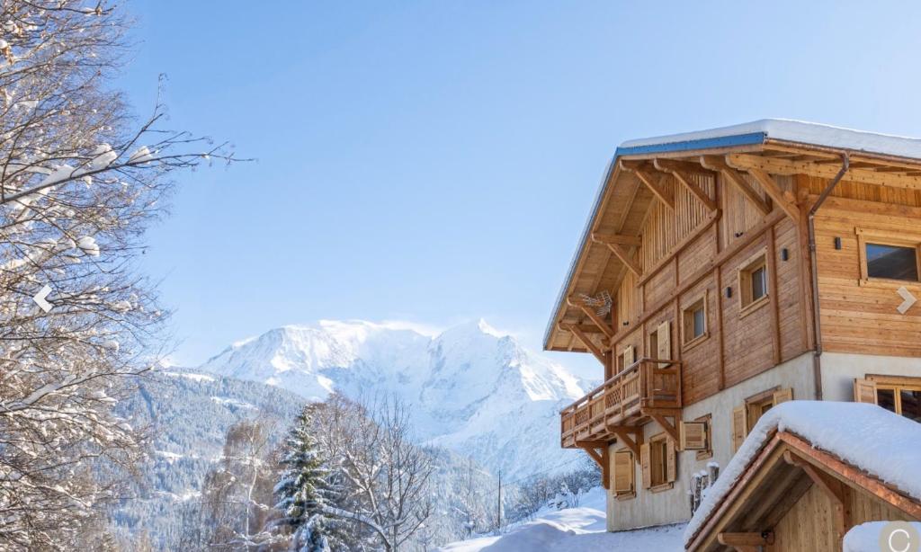 un bâtiment sous la neige avec des montagnes en arrière-plan dans l'établissement Chalet prestige Saint Gervais les Bains, à Saint-Gervais-les-Bains