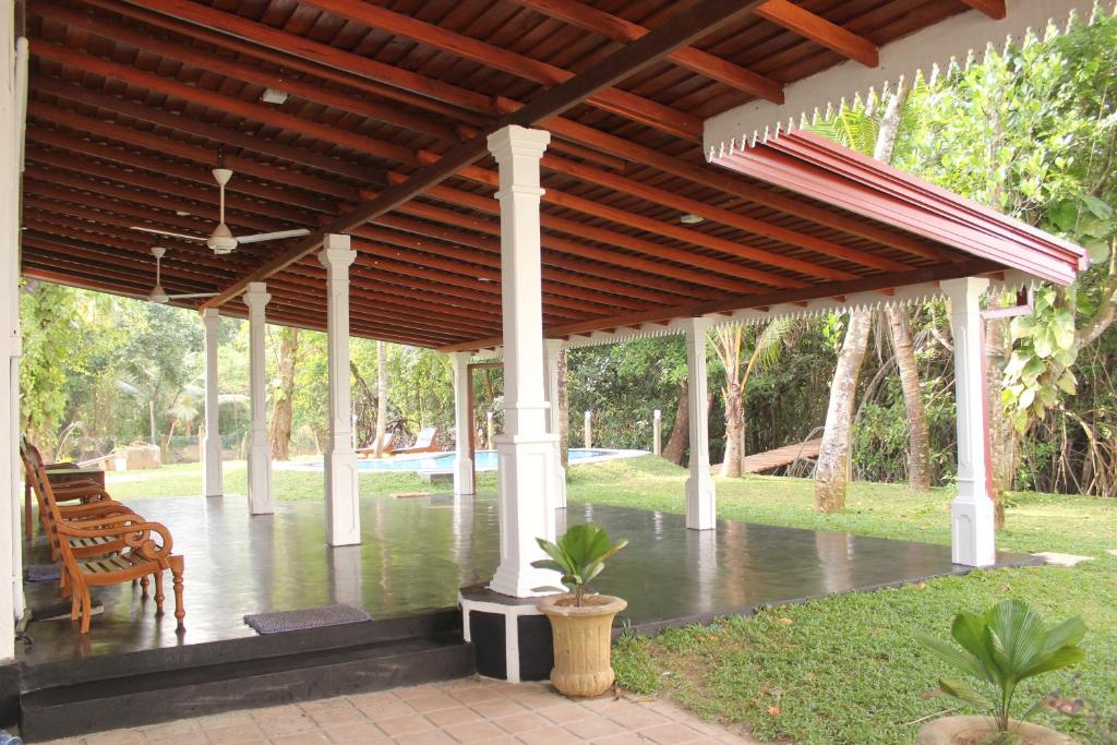 a pavilion with a wooden roof and a table and chairs at Sethra Villa Bentota in Bentota