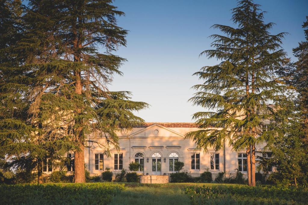 un vieux manoir avec des arbres devant lui dans l'établissement Château Le Pape B&B, à Léognan