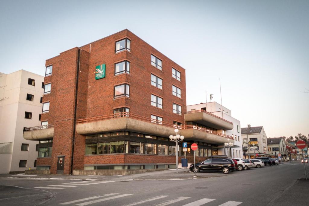 um edifício de tijolos vermelhos com um carro estacionado em frente em Quality Hotel Grand Steinkjer em Steinkjer