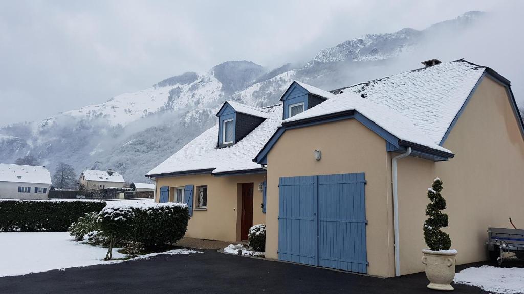a house with a snow covered roof in front of a mountain at La maison de Lucie in Gère-Belesten