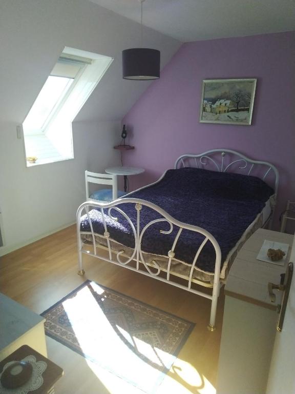 une chambre avec un lit avec un mur violet dans l'établissement Chambre en maison chez l habitant, à Joué-lès-Tours