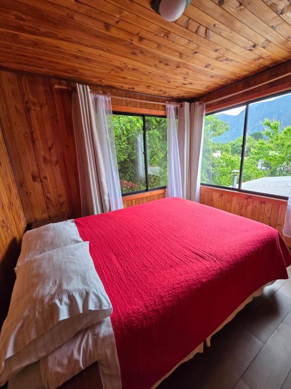Cabaña 8 a 9 personas ideal 2 matrimonios y niños في كونياريبي: غرفة نوم بسرير احمر مع نافذة كبيرة