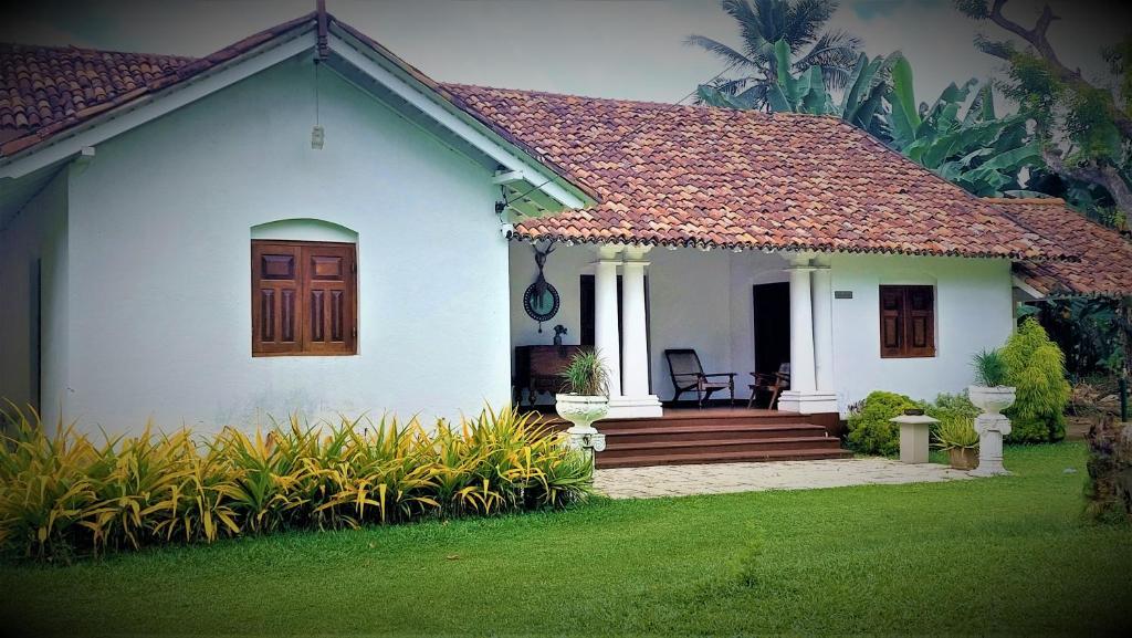 a white house with a wooden door and a porch at Tamarind Villa in Kelaniya