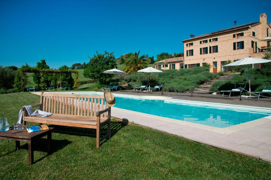 un banco de madera sentado en el césped junto a una piscina en Casal dei Fichi, en Francavilla dʼEte