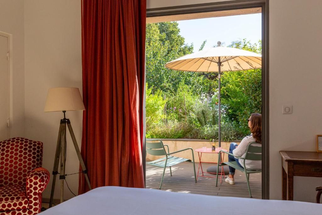a woman sitting at a table with an umbrella on a patio at Hôtel 96 in Marseille