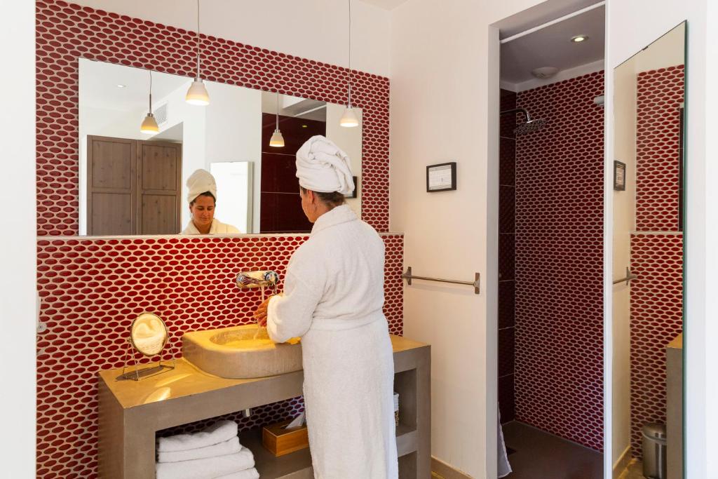 a woman is standing in front of a bathroom mirror at Hôtel 96 in Marseille