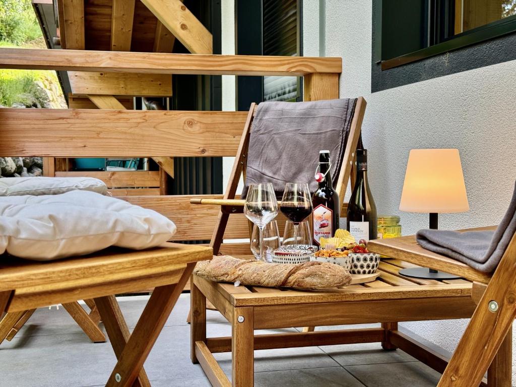 une chaise en bois avec une table et des verres à vin dans l'établissement Les cimes de l alpage - Duplex luxe, Ski in Ski out, à Combloux