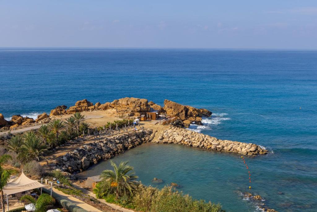 an aerial view of a beach with rocks and the ocean at Queens Bay Hotel in Paphos