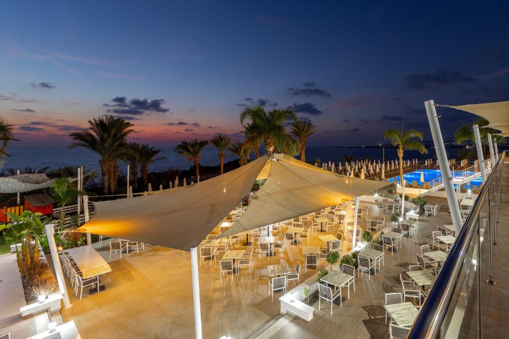 a group of tables and chairs on a balcony at night at Queens Bay Hotel in Paphos