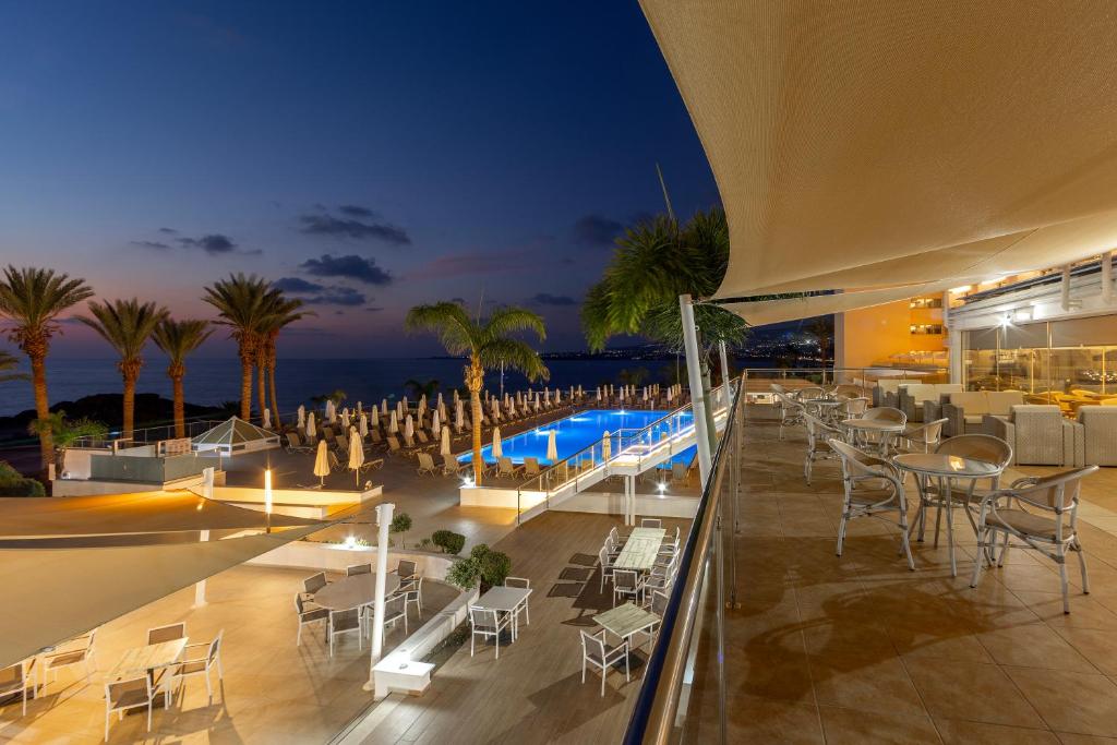 a resort with a pool and tables and chairs at Queens Bay Hotel in Paphos