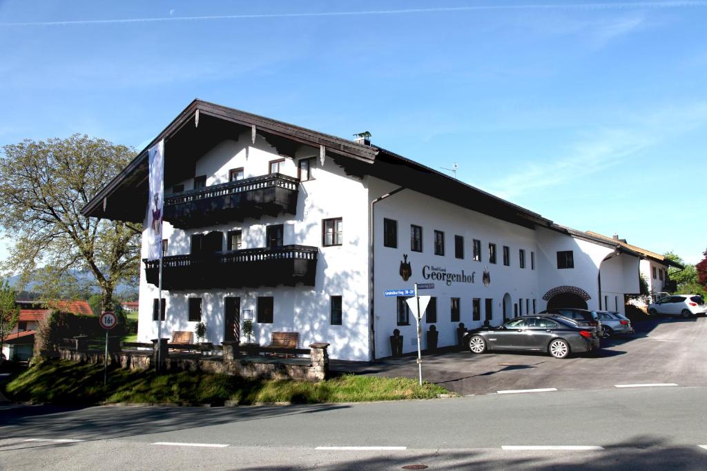 a white building with a car parked in a parking lot at Hotel Garni Georgenhof Adults Only in Rimsting