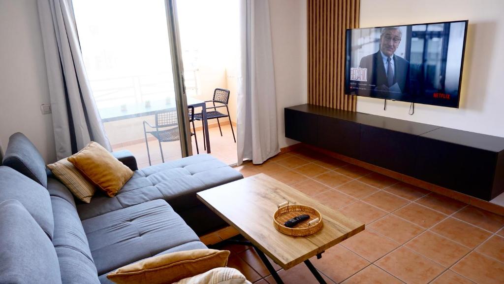 een woonkamer met een bank en een flatscreen-tv bij Tejita Beach Apartment in Granadilla de Abona