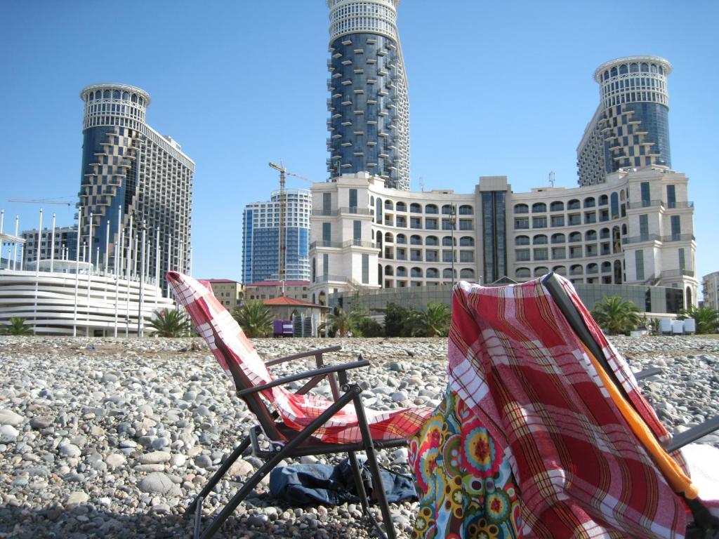 duas cadeiras sentadas numa praia em frente a uma cidade em My Batumi Apartments em Batumi