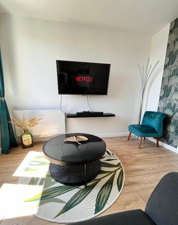 un salon avec une table et une télévision dans l'établissement Le petit cocon de Kintana -Disney-Parking, à Meaux